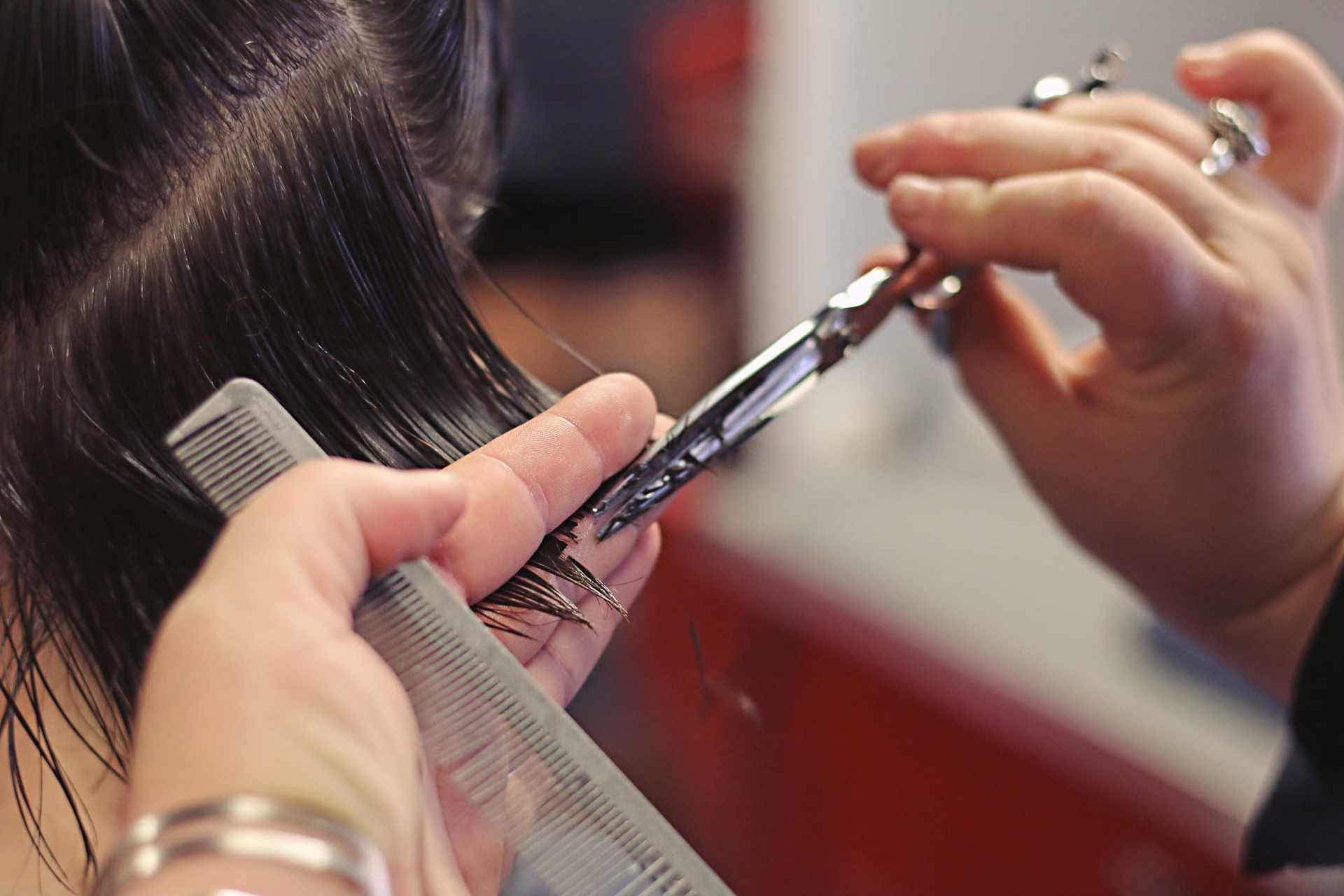 Hair being neatly trimmed with scissors and comb in a close-up salon setting.